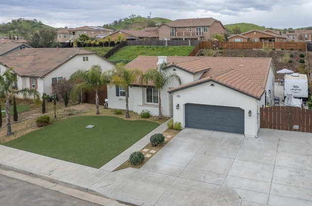 view of front of home featuring a front yard, fence, concrete driveway, a garage, and a tile roof