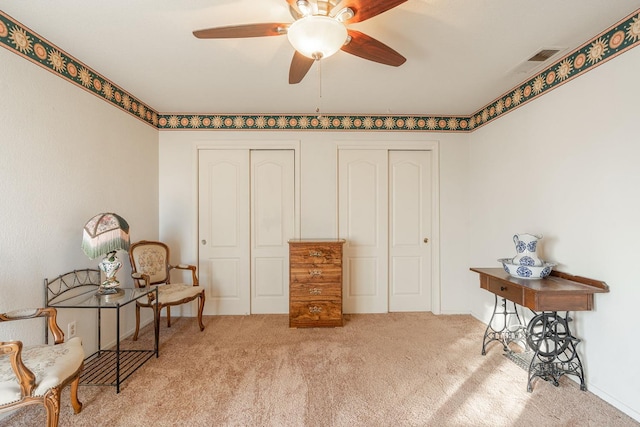 sitting room featuring carpet, visible vents, and ceiling fan