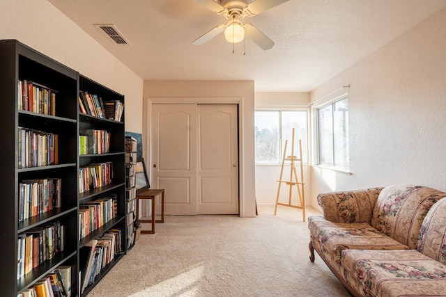 sitting room with visible vents, ceiling fan, a textured ceiling, and carpet