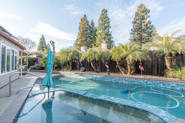 view of swimming pool featuring a fenced backyard and a pool with connected hot tub