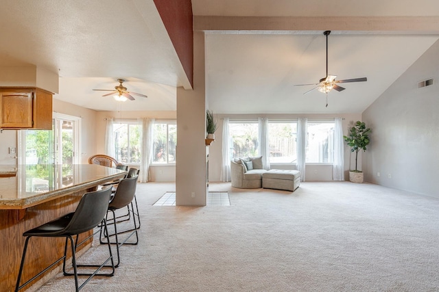 living area featuring visible vents, lofted ceiling, light colored carpet, and ceiling fan