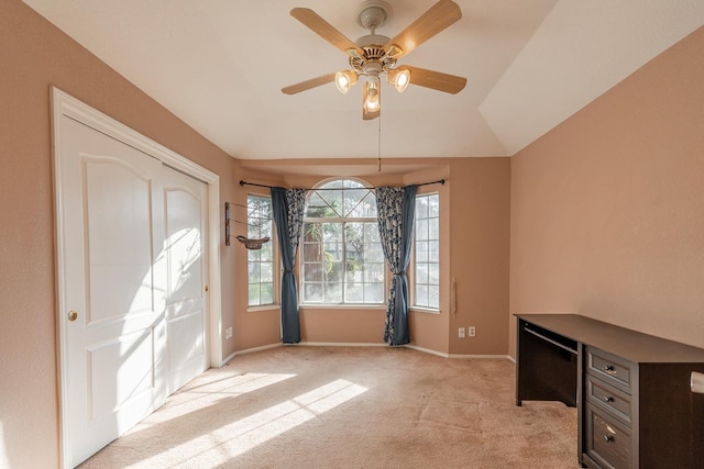 interior space featuring a ceiling fan, vaulted ceiling, light colored carpet, and baseboards