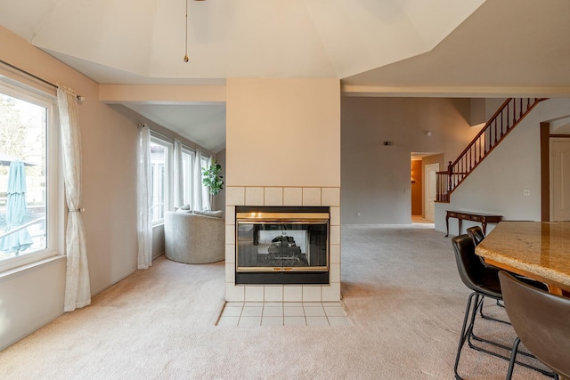 carpeted living area with stairs, high vaulted ceiling, a healthy amount of sunlight, and a fireplace