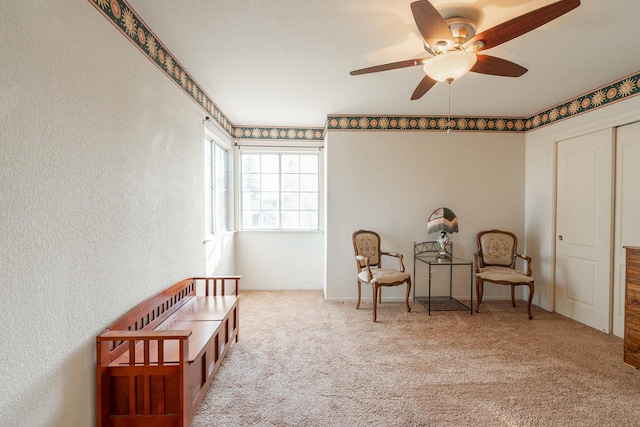 living area with baseboards, a ceiling fan, and carpet floors