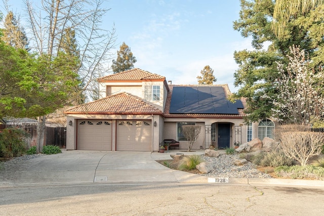 mediterranean / spanish home featuring stucco siding, concrete driveway, a garage, solar panels, and a tiled roof