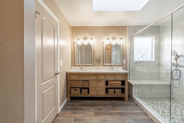 bathroom with a sink, a skylight, wood finished floors, and a shower stall