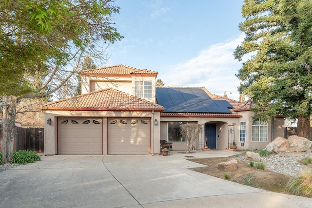 mediterranean / spanish-style house with stucco siding, roof mounted solar panels, an attached garage, and a tiled roof