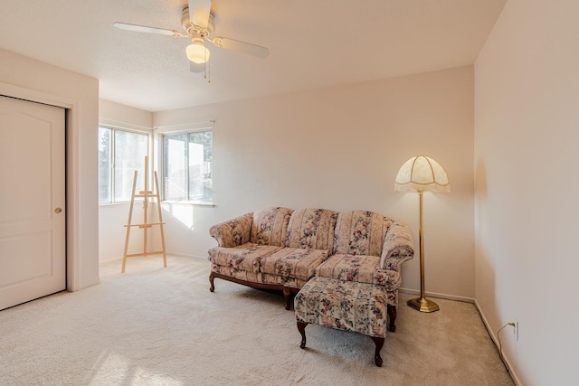 living area featuring baseboards, a ceiling fan, and carpet flooring