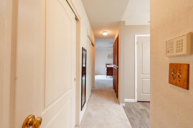 corridor with baseboards and light carpet