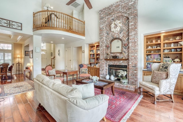 living room with visible vents, built in features, a fireplace, and wood-type flooring