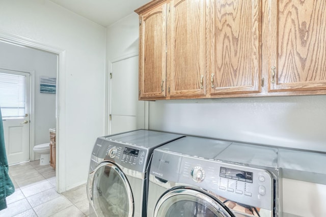 clothes washing area with light tile patterned flooring, cabinet space, and washing machine and clothes dryer