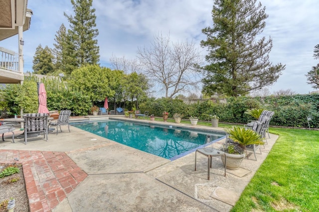 view of swimming pool featuring a fenced in pool, a patio, a lawn, and fence