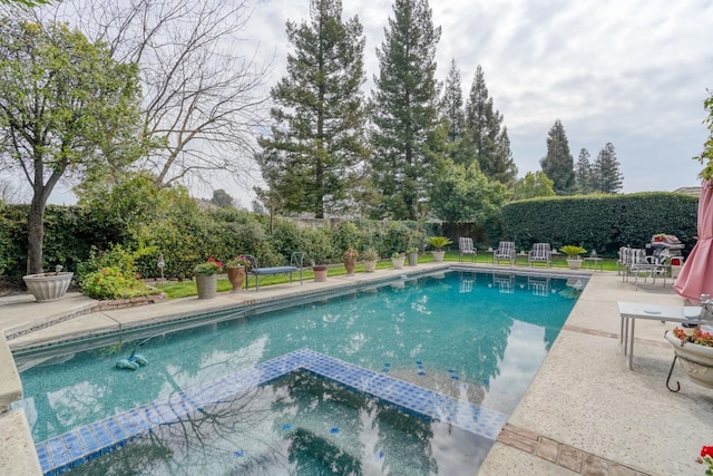 view of swimming pool with a patio area, a pool with connected hot tub, and fence