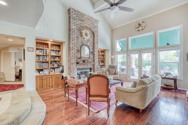 living area featuring plenty of natural light, a brick fireplace, french doors, and wood finished floors