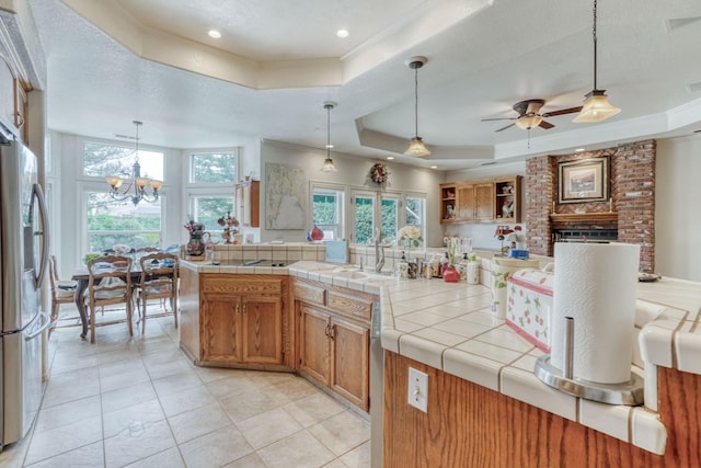 kitchen featuring plenty of natural light, a raised ceiling, stainless steel refrigerator with ice dispenser, and a sink