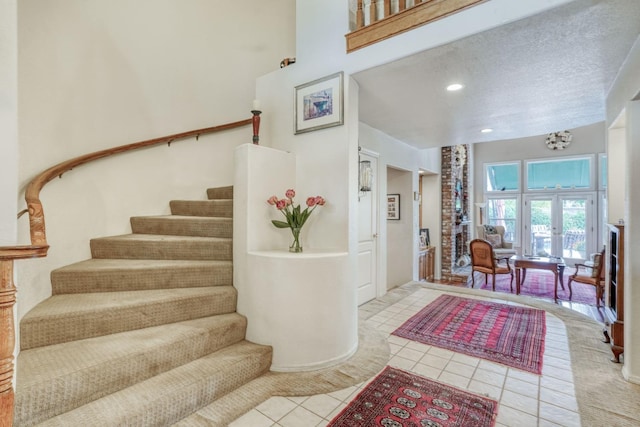 stairs featuring tile patterned flooring, recessed lighting, a towering ceiling, and a textured ceiling