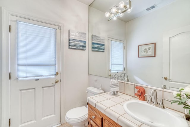 half bath with vanity, toilet, and visible vents