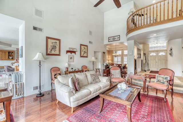 living room with visible vents, ceiling fan with notable chandelier, and wood finished floors