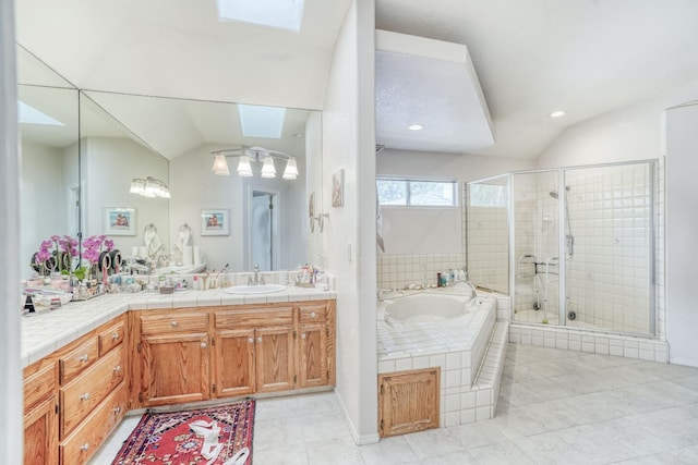 full bathroom with vanity, lofted ceiling with skylight, a garden tub, and a stall shower