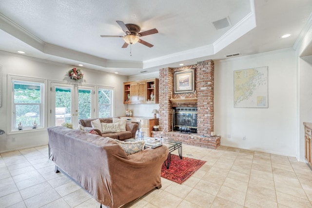 living area with a raised ceiling, a fireplace, french doors, and ornamental molding