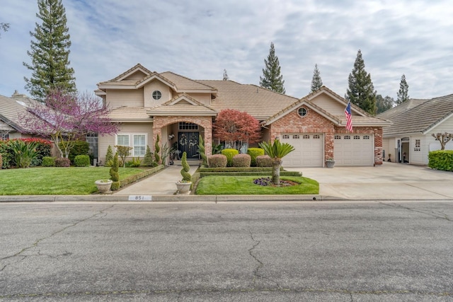 traditional-style home with brick siding, a front lawn, a tiled roof, concrete driveway, and an attached garage