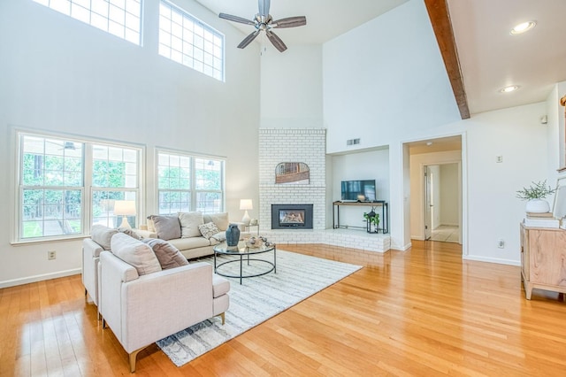 living area featuring visible vents, beam ceiling, a fireplace, light wood finished floors, and baseboards