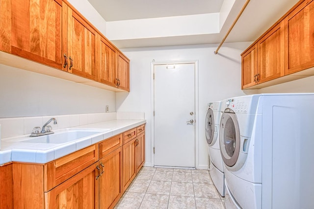 washroom featuring washer and dryer, light tile patterned flooring, cabinet space, and a sink