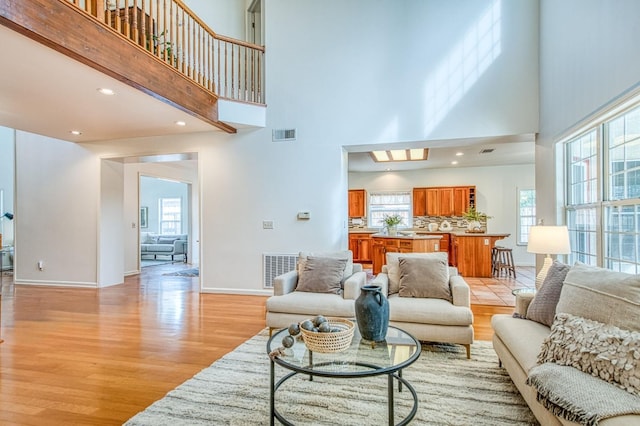 living area with light wood-style floors, visible vents, and baseboards