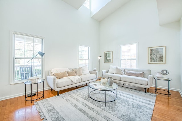 living area featuring a towering ceiling, baseboards, and wood finished floors