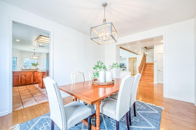 dining room with baseboards, recessed lighting, stairs, light wood-style floors, and a notable chandelier