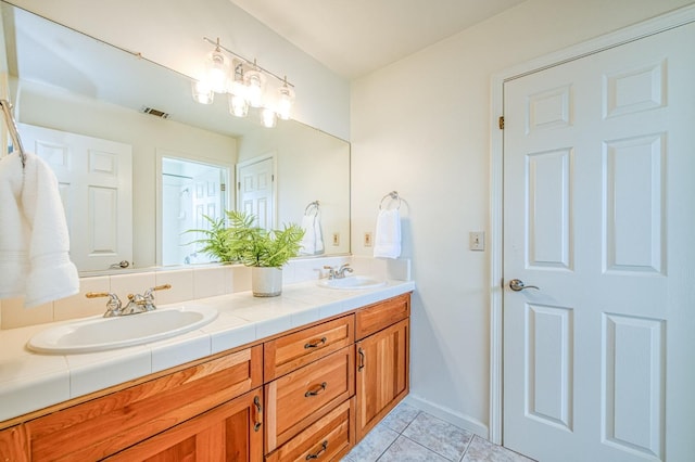 full bathroom with a sink, visible vents, double vanity, and tile patterned floors