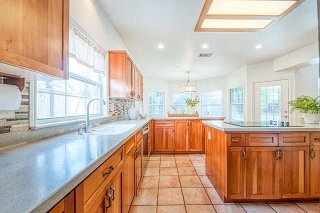 kitchen featuring visible vents, a sink, brown cabinets, a peninsula, and stainless steel dishwasher