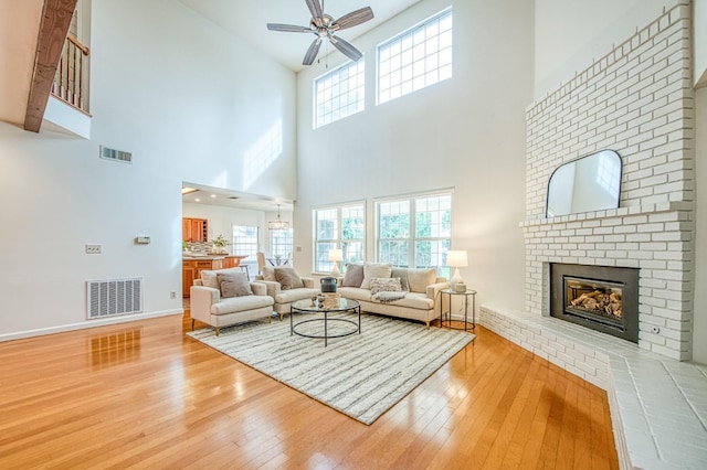 living area featuring a fireplace, light wood-style floors, visible vents, and ceiling fan