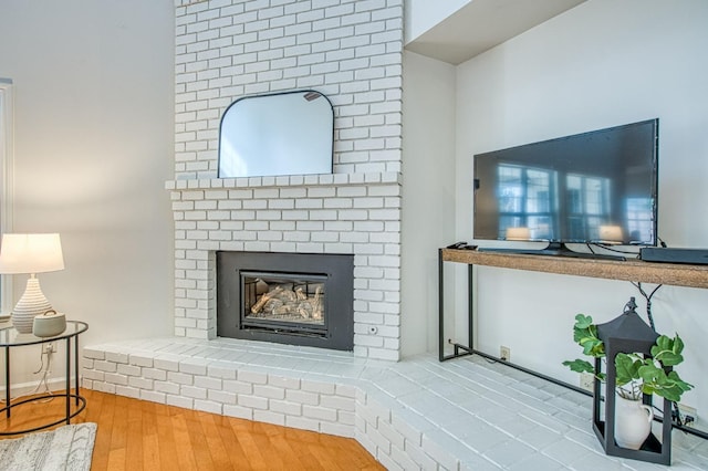 living room with a brick fireplace and wood finished floors