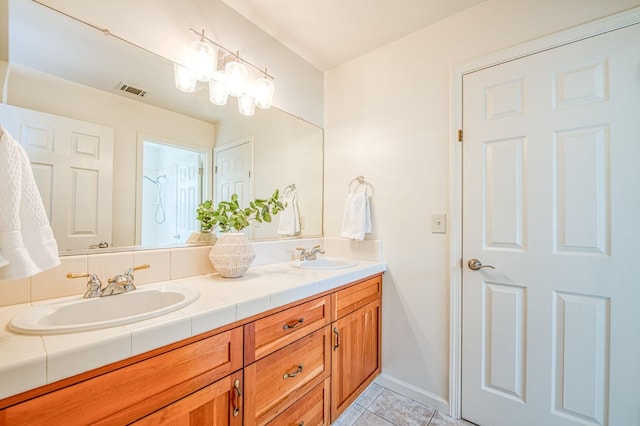 bathroom featuring a sink, visible vents, double vanity, and tile patterned floors