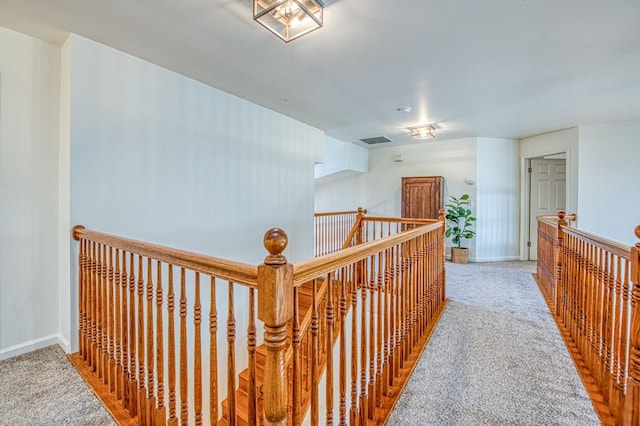 corridor featuring visible vents, carpet floors, and baseboards