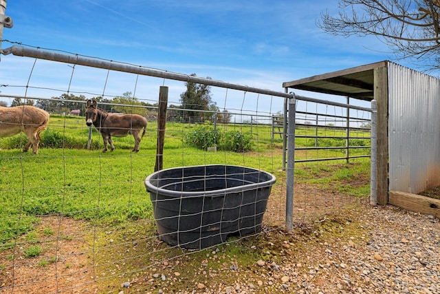 view of yard featuring an outbuilding, a rural view, and fence