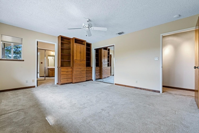 unfurnished bedroom featuring visible vents, baseboards, ceiling fan, a textured ceiling, and light colored carpet