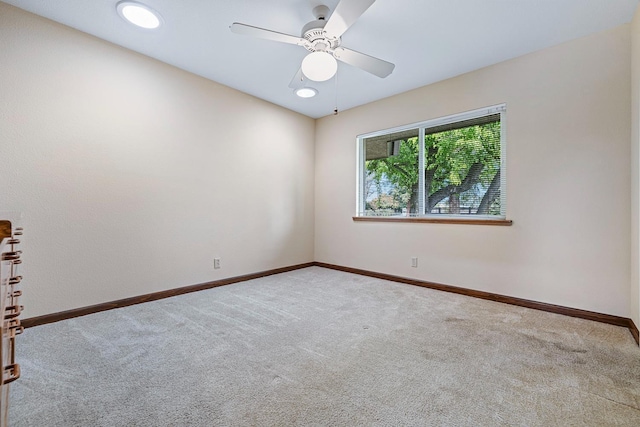 carpeted spare room with ceiling fan and baseboards