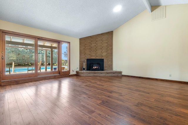 unfurnished living room featuring visible vents, beam ceiling, a textured ceiling, wood finished floors, and a fireplace