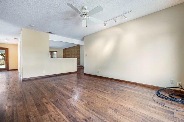 unfurnished living room featuring visible vents, a textured ceiling, baseboards, and wood-type flooring