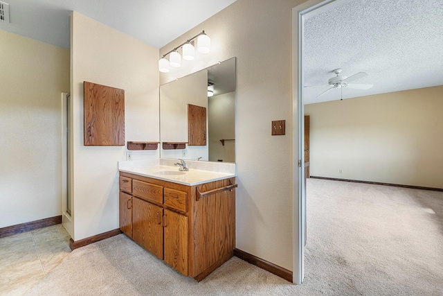 bathroom featuring baseboards, a textured ceiling, ceiling fan, and vanity