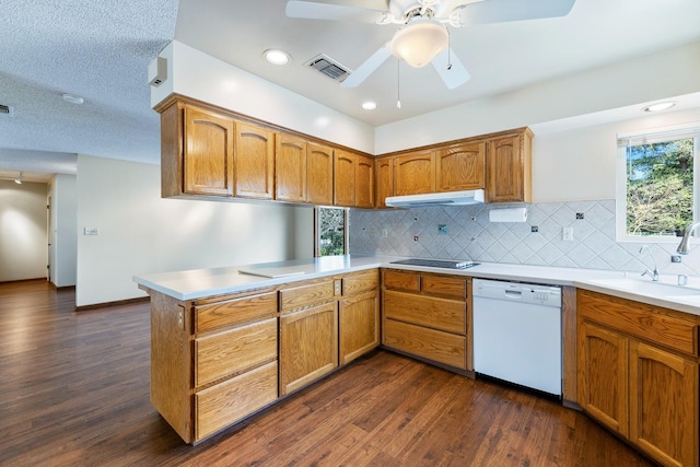 kitchen with visible vents, a peninsula, a sink, under cabinet range hood, and dishwasher