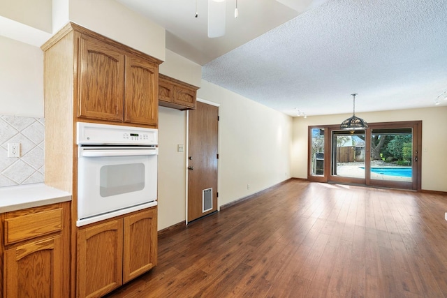 kitchen with visible vents, dark wood-type flooring, light countertops, white oven, and a textured ceiling