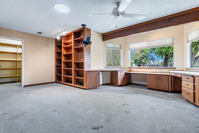 interior space featuring baseboards, visible vents, built in study area, a textured ceiling, and light colored carpet