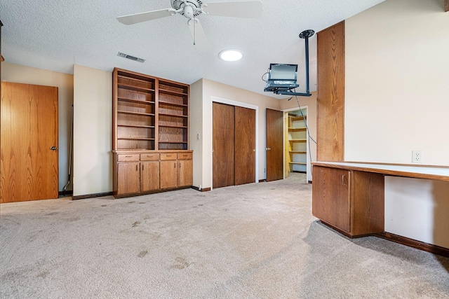 unfurnished living room with visible vents, light carpet, a ceiling fan, a textured ceiling, and baseboards