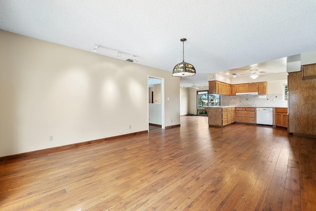 kitchen with open floor plan, wood-type flooring, light countertops, decorative backsplash, and dishwasher