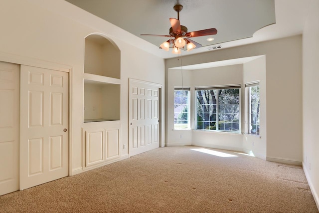 unfurnished bedroom with visible vents, two closets, carpet flooring, baseboards, and ceiling fan