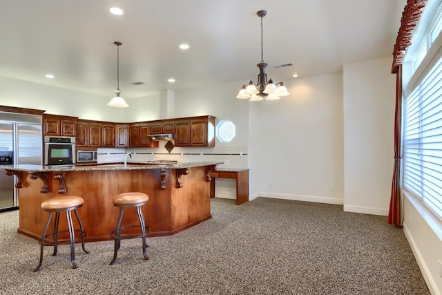 kitchen featuring visible vents, under cabinet range hood, recessed lighting, appliances with stainless steel finishes, and a kitchen breakfast bar