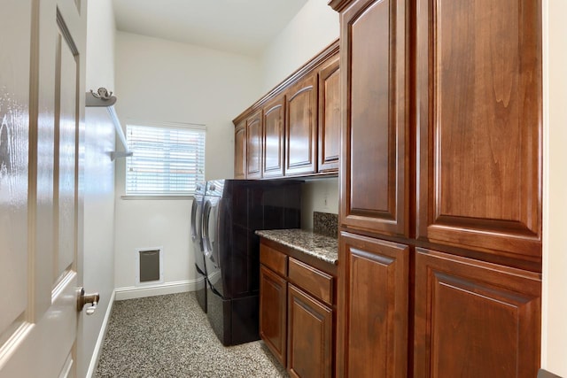 laundry area featuring washing machine and dryer, cabinet space, and baseboards